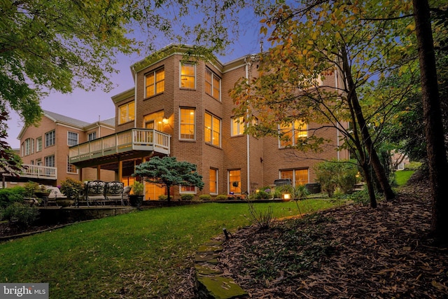 back house at dusk featuring a lawn