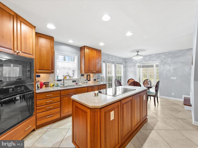 kitchen with sink, light tile patterned floors, a kitchen island, decorative backsplash, and black appliances