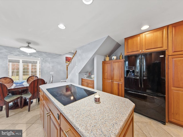 kitchen with light stone countertops, black appliances, a center island, and light tile patterned flooring