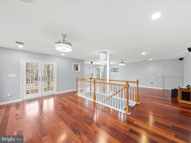 empty room featuring wood-type flooring, french doors, and a chandelier