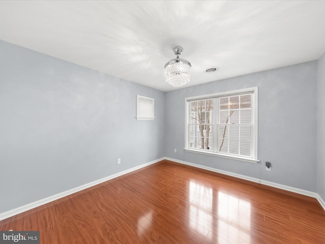 unfurnished room with hardwood / wood-style flooring and an inviting chandelier