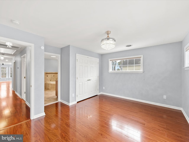 unfurnished bedroom featuring hardwood / wood-style floors, a notable chandelier, and a closet