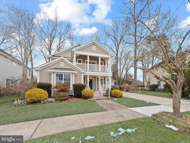 greek revival house with a balcony, a porch, and a front lawn