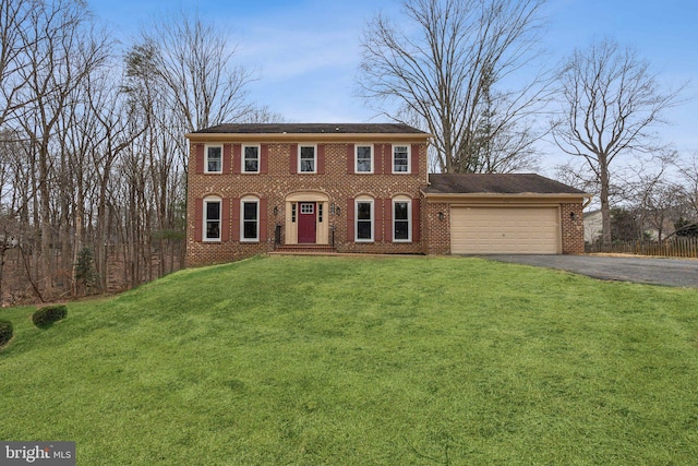 colonial-style house with aphalt driveway, a front yard, brick siding, and a garage