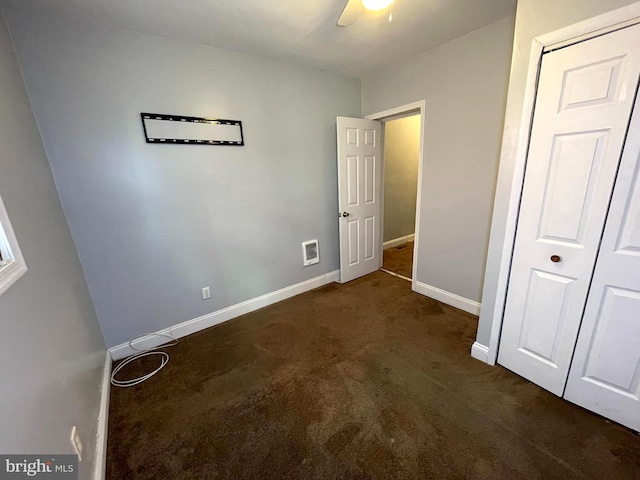 unfurnished bedroom with ceiling fan and dark colored carpet