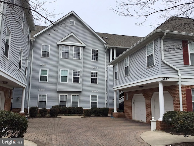 view of front of home with a garage, decorative driveway, and brick siding