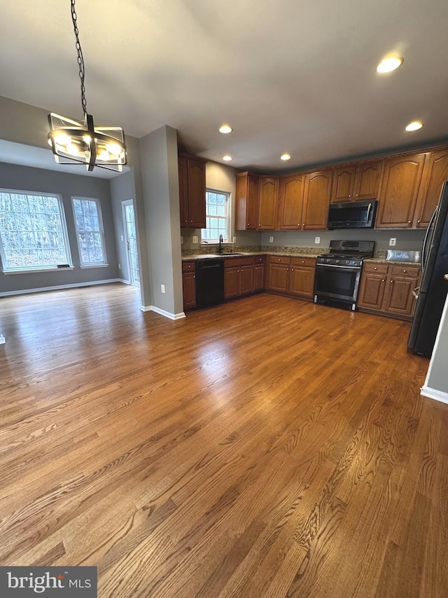 kitchen with pendant lighting, black dishwasher, sink, dark hardwood / wood-style flooring, and gas stove