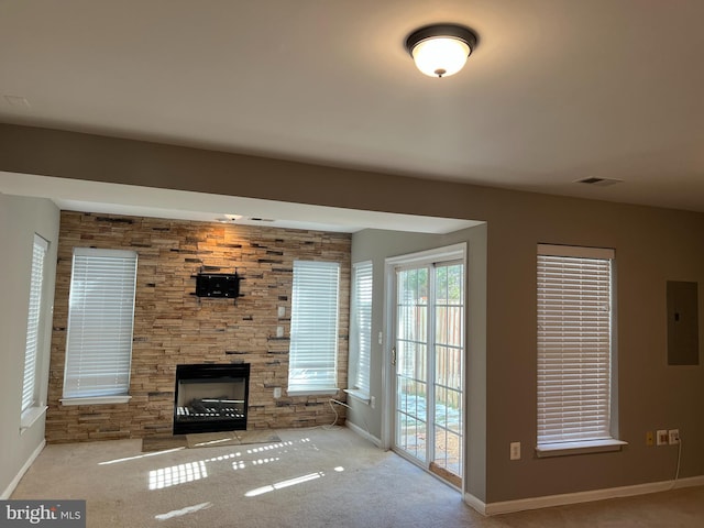 unfurnished living room featuring light colored carpet, a stone fireplace, and electric panel