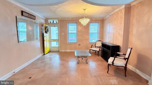 living area featuring an inviting chandelier, crown molding, baseboards, and a textured ceiling