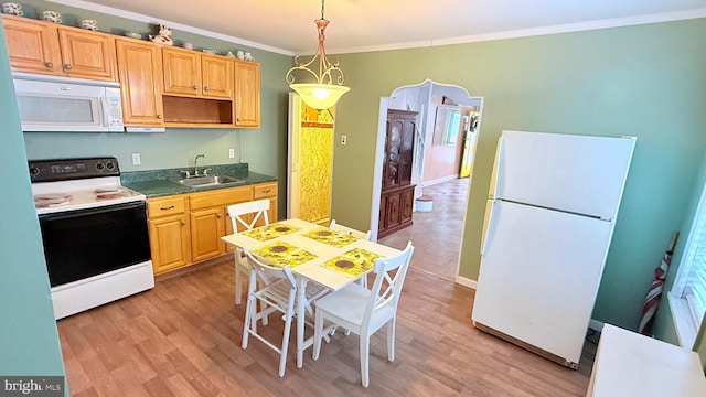 kitchen with white appliances, dark countertops, crown molding, light wood-type flooring, and a sink