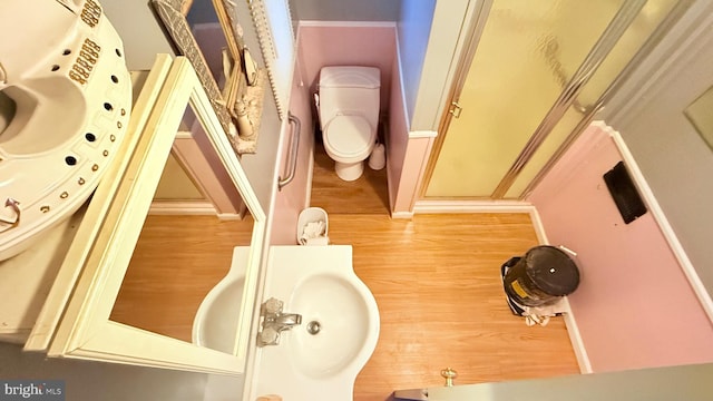 bathroom featuring a stall shower, toilet, and wood finished floors