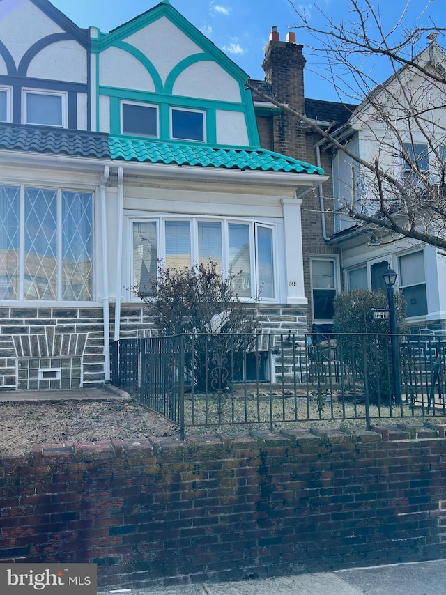 exterior space with a fenced front yard, a tile roof, a chimney, and stucco siding