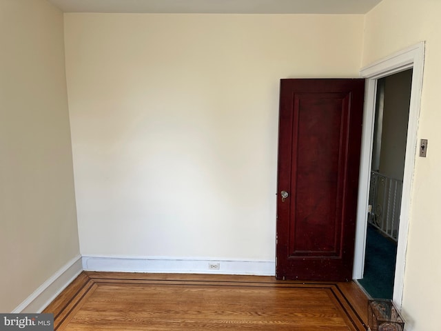 spare room featuring baseboards and wood finished floors