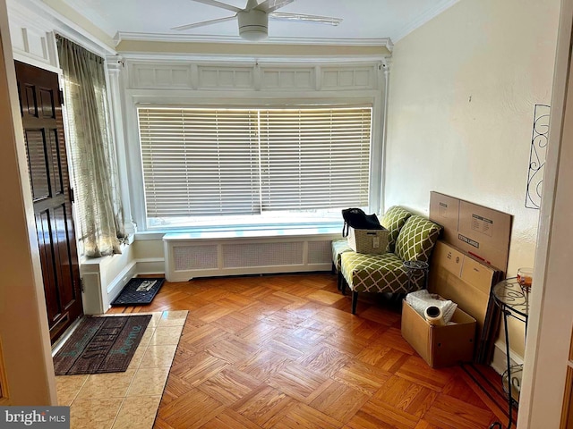 living area with ornamental molding, a wealth of natural light, baseboards, and radiator heating unit