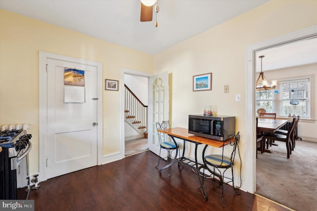 office area with dark hardwood / wood-style flooring and ceiling fan with notable chandelier