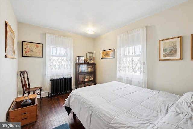 bedroom with radiator heating unit and dark hardwood / wood-style flooring