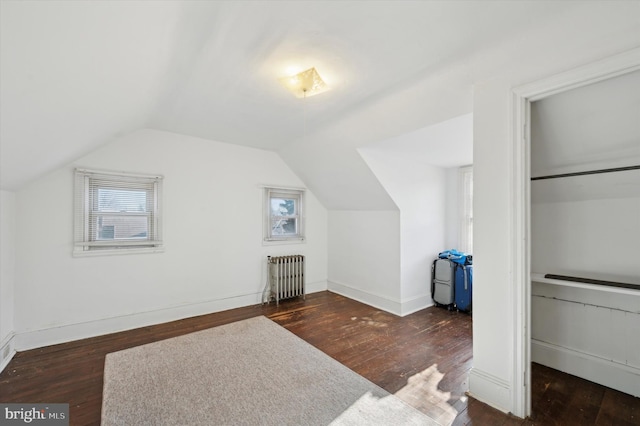 additional living space with dark wood-type flooring, lofted ceiling, and radiator heating unit