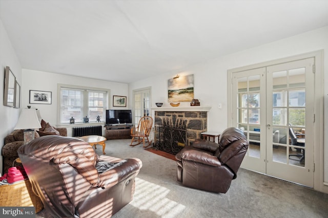 carpeted living room featuring a fireplace, french doors, and radiator heating unit