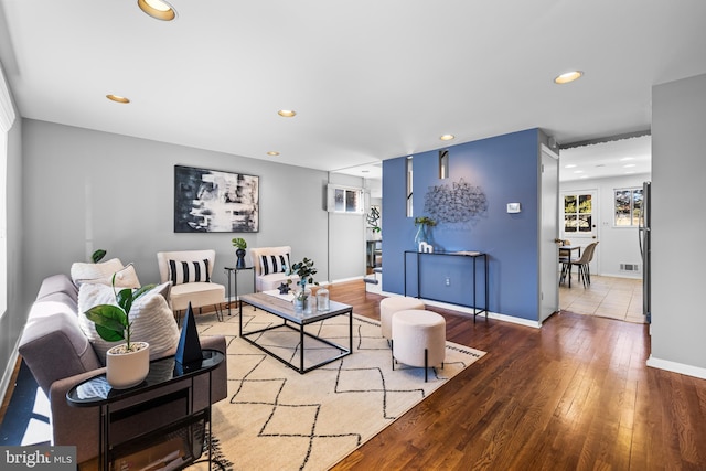 living area with baseboards, wood finished floors, visible vents, and recessed lighting