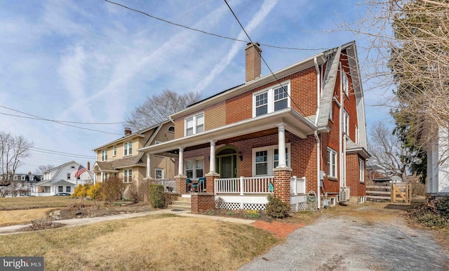 view of front of home featuring brick siding, a porch, and a chimney