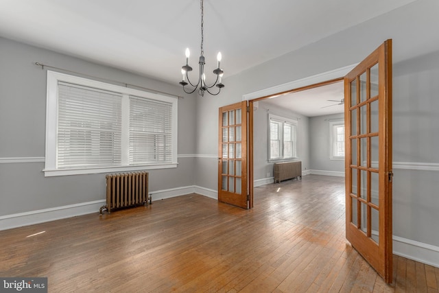 unfurnished room with hardwood / wood-style flooring, radiator, french doors, and baseboards