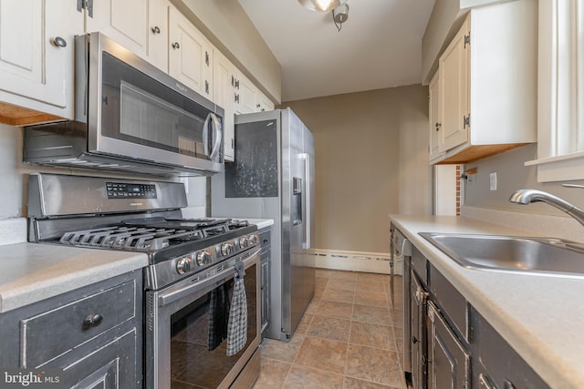 kitchen with white cabinets, stainless steel appliances, light countertops, and a sink