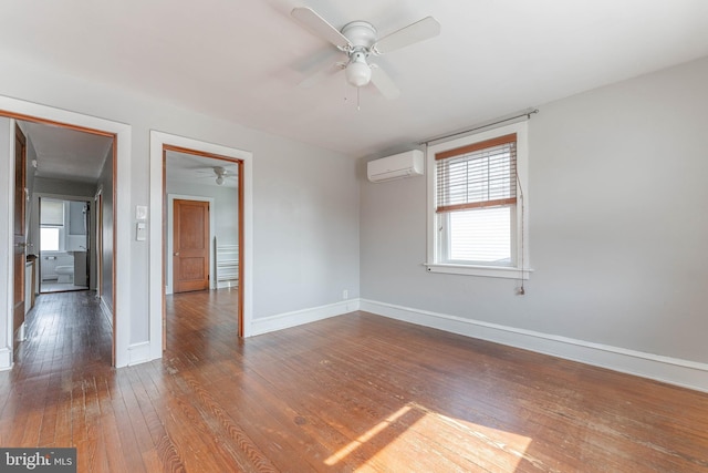 unfurnished room featuring baseboards, an AC wall unit, a ceiling fan, and wood-type flooring