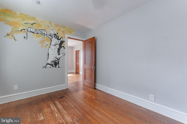 empty room with a ceiling fan, baseboards, and wood-type flooring