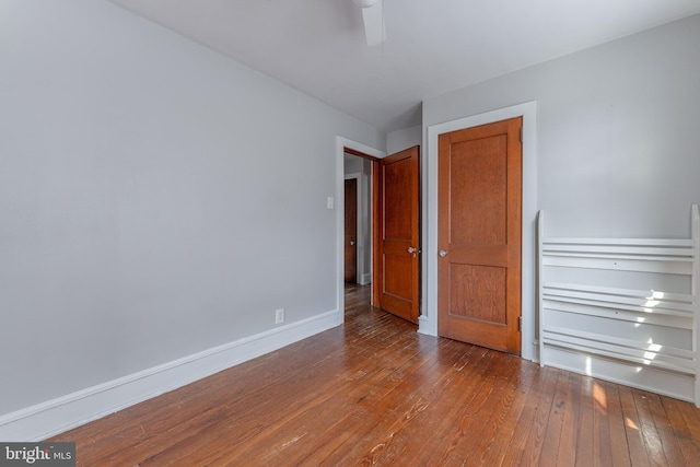 unfurnished bedroom featuring ceiling fan, baseboards, and wood-type flooring