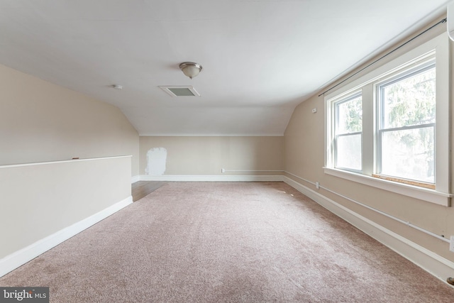 additional living space featuring carpet flooring, baseboards, and vaulted ceiling