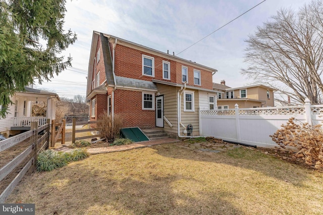 rear view of property with a yard, a fenced backyard, and brick siding