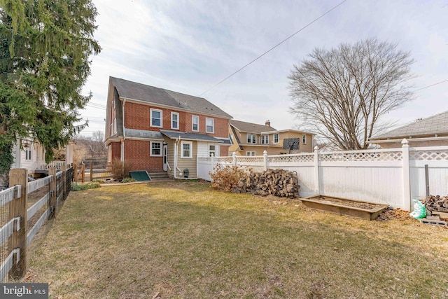 back of property with a yard, a fenced backyard, and brick siding