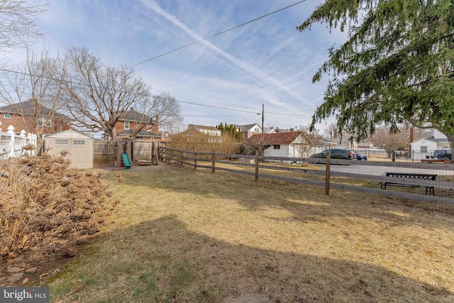 view of yard featuring a fenced backyard, an outbuilding, and a storage shed