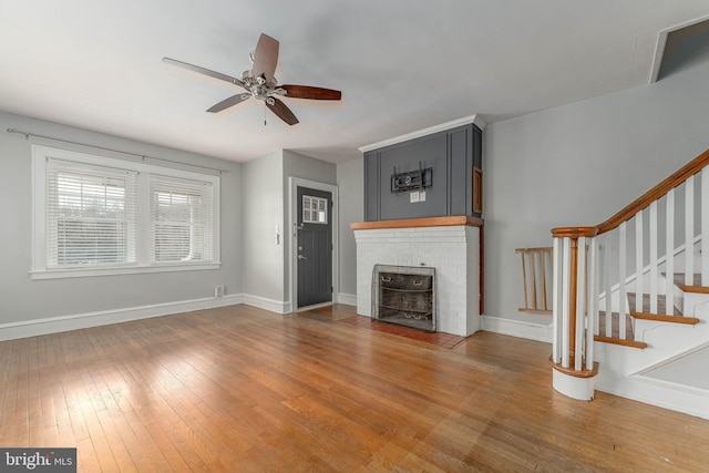 unfurnished living room with stairway, wood-type flooring, baseboards, and a ceiling fan