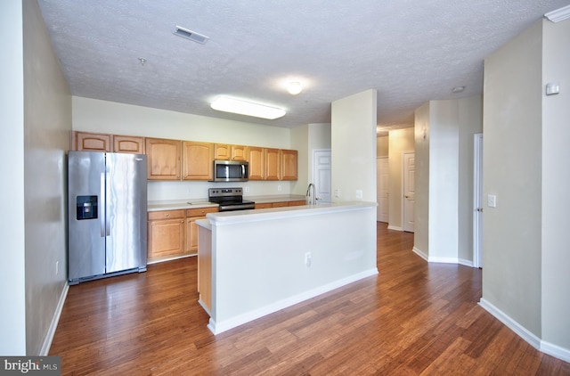 kitchen with dark wood finished floors, stainless steel appliances, light countertops, visible vents, and baseboards