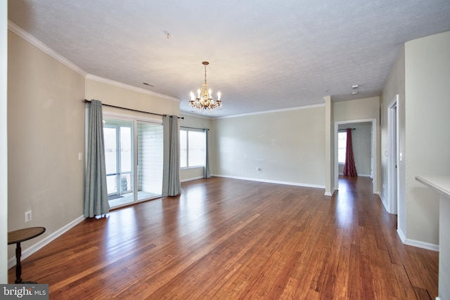 unfurnished living room featuring a notable chandelier, crown molding, baseboards, and wood finished floors