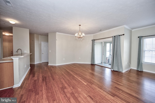 unfurnished living room featuring a textured ceiling, a chandelier, dark wood finished floors, and a wealth of natural light