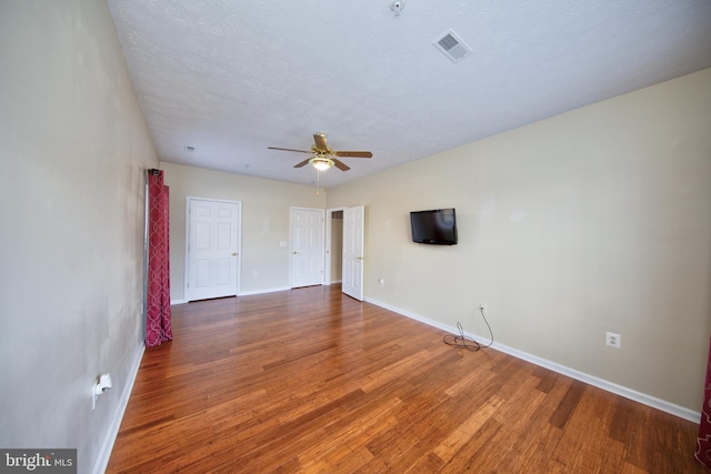 spare room featuring visible vents, ceiling fan, a textured ceiling, wood finished floors, and baseboards