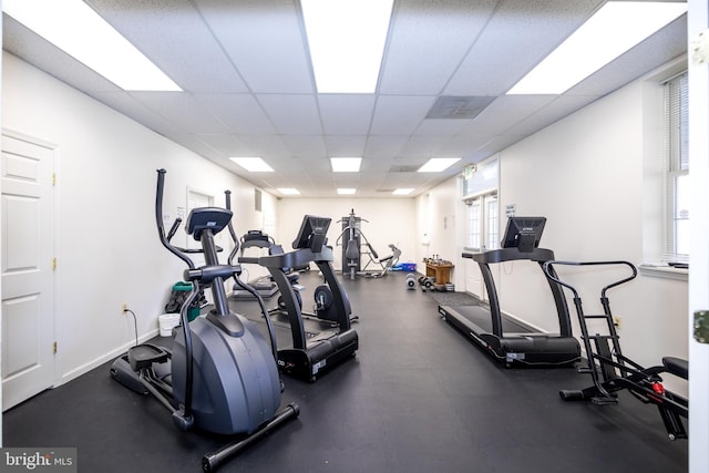 workout area with a paneled ceiling and baseboards