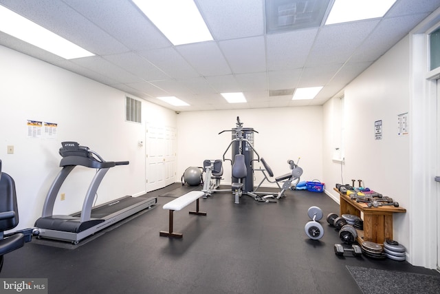 workout area with baseboards, visible vents, and a drop ceiling