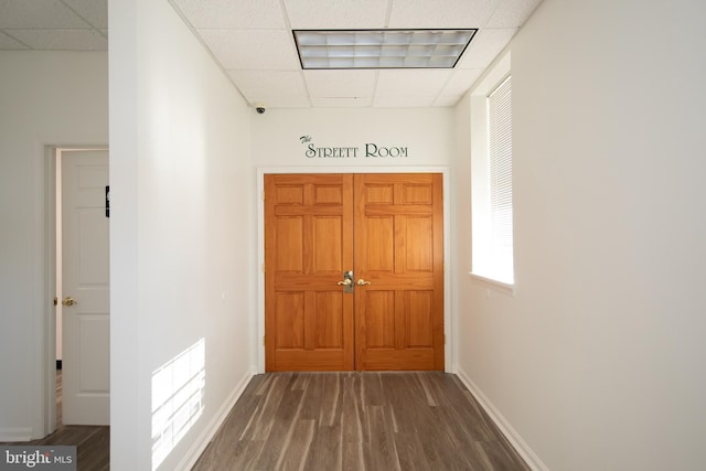 corridor with a drop ceiling, wood finished floors, visible vents, and baseboards