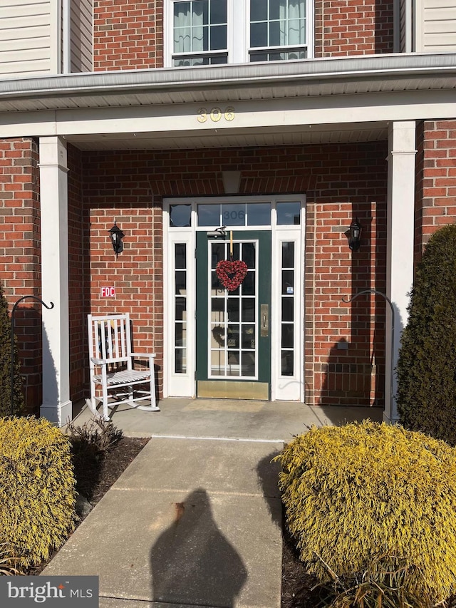 property entrance with covered porch and brick siding