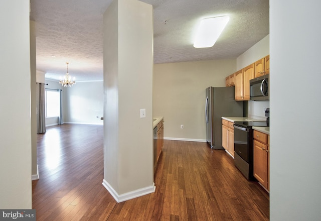 kitchen with a textured ceiling, light countertops, appliances with stainless steel finishes, and dark wood-type flooring