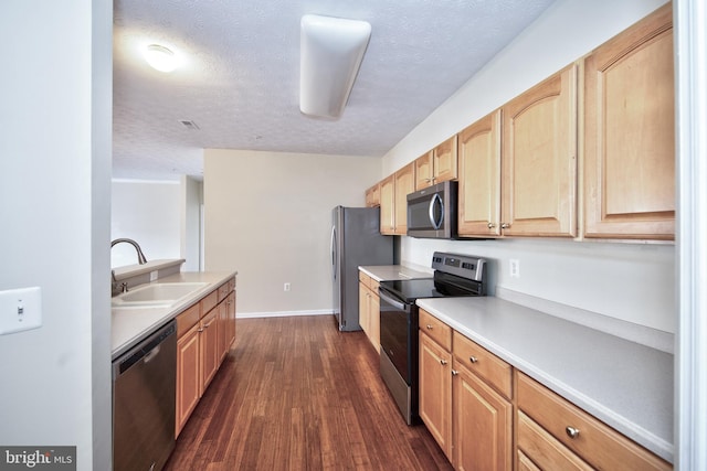 kitchen with light countertops, appliances with stainless steel finishes, dark wood-type flooring, light brown cabinets, and a sink