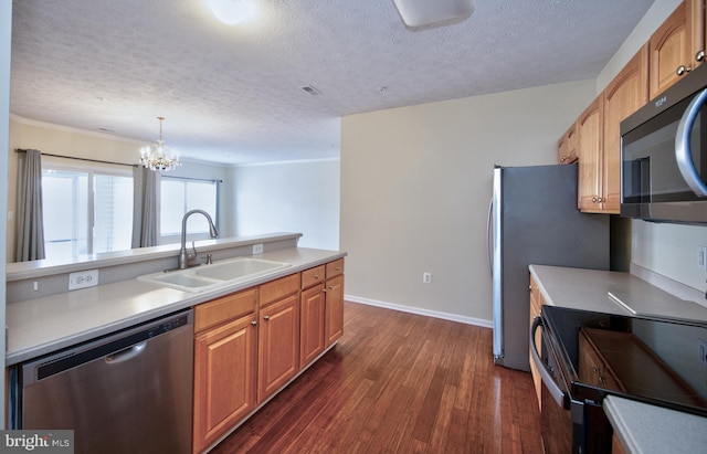 kitchen with stainless steel appliances, light countertops, a sink, and dark wood finished floors