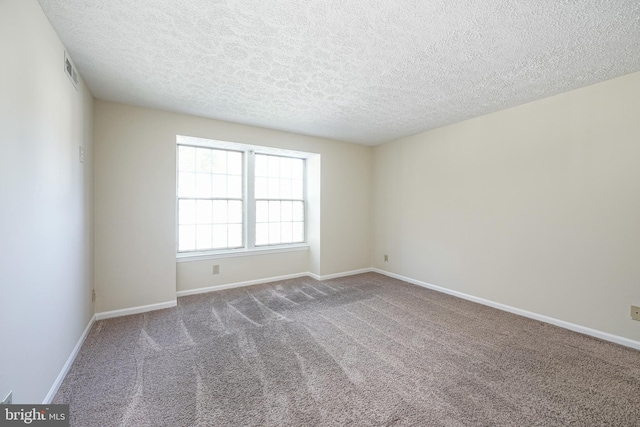 spare room with baseboards, a textured ceiling, visible vents, and carpet flooring