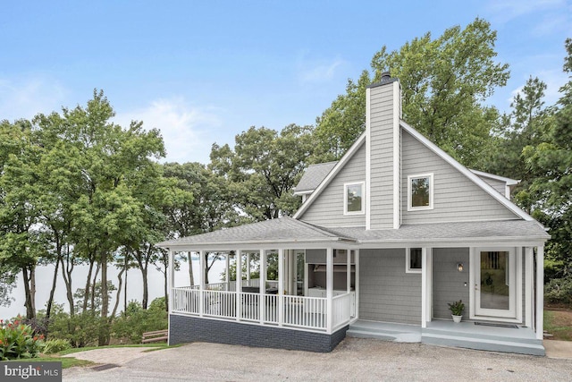 farmhouse inspired home with a chimney, a porch, and roof with shingles