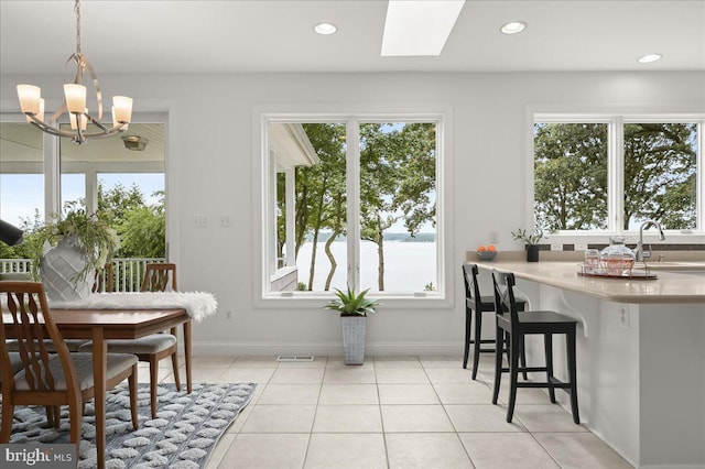 dining area with light tile patterned floors, recessed lighting, a skylight, baseboards, and an inviting chandelier