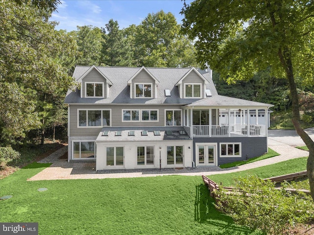 rear view of property featuring an attached garage, driveway, a lawn, and french doors