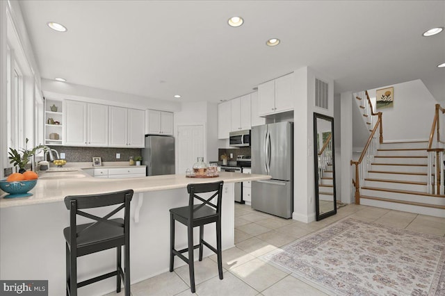 kitchen with tasteful backsplash, a peninsula, stainless steel appliances, open shelves, and a sink